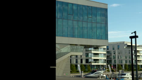 modern glass building with a distinct architectural design, standing under a clear blue sky