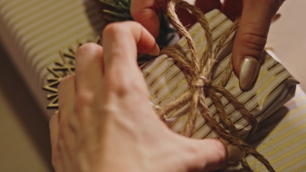 Woman's Hand Wrapping A Gift With A Rustic, Festive Theme. - closeup shot