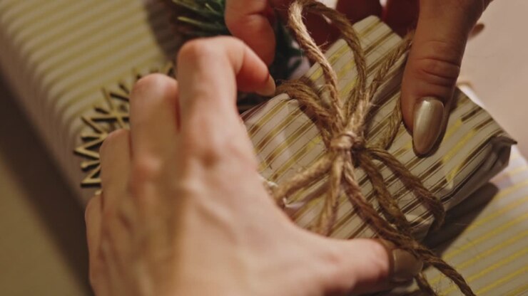 Woman's Hand Wrapping A Gift With A Rustic, Festive Theme. - closeup shot