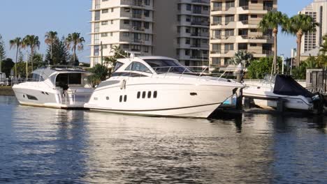 a yacht moves past urban buildings along a river