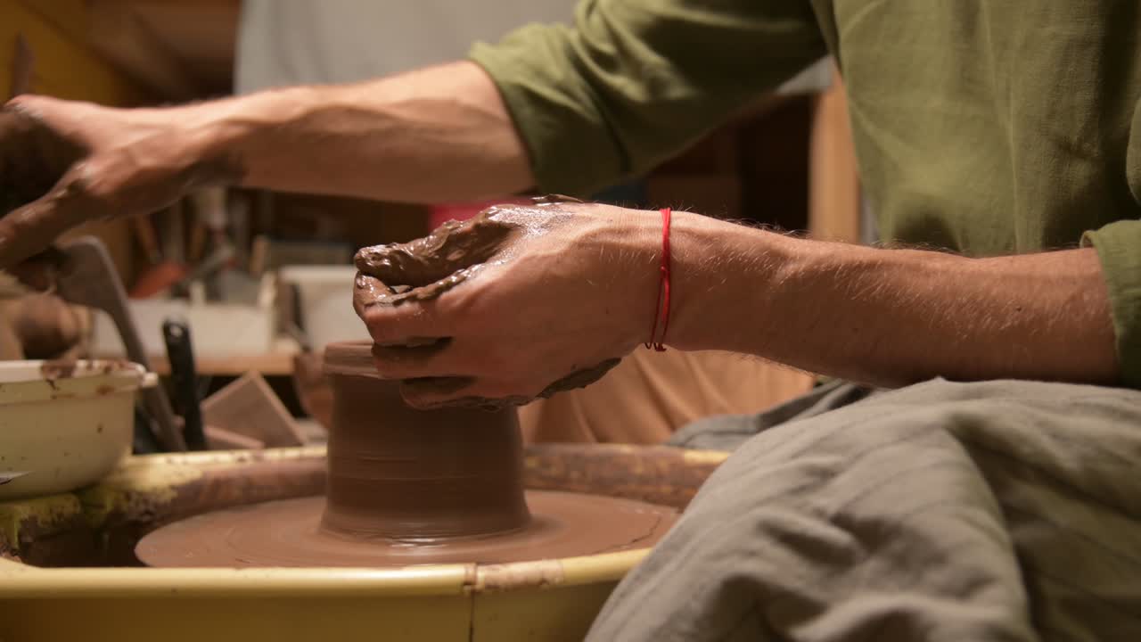 Primer plano de un alfarero haciendo un cuenco de arcilla en un torno de alfarero.