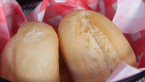 hand reaching for rolls on a red and white checkered napkin