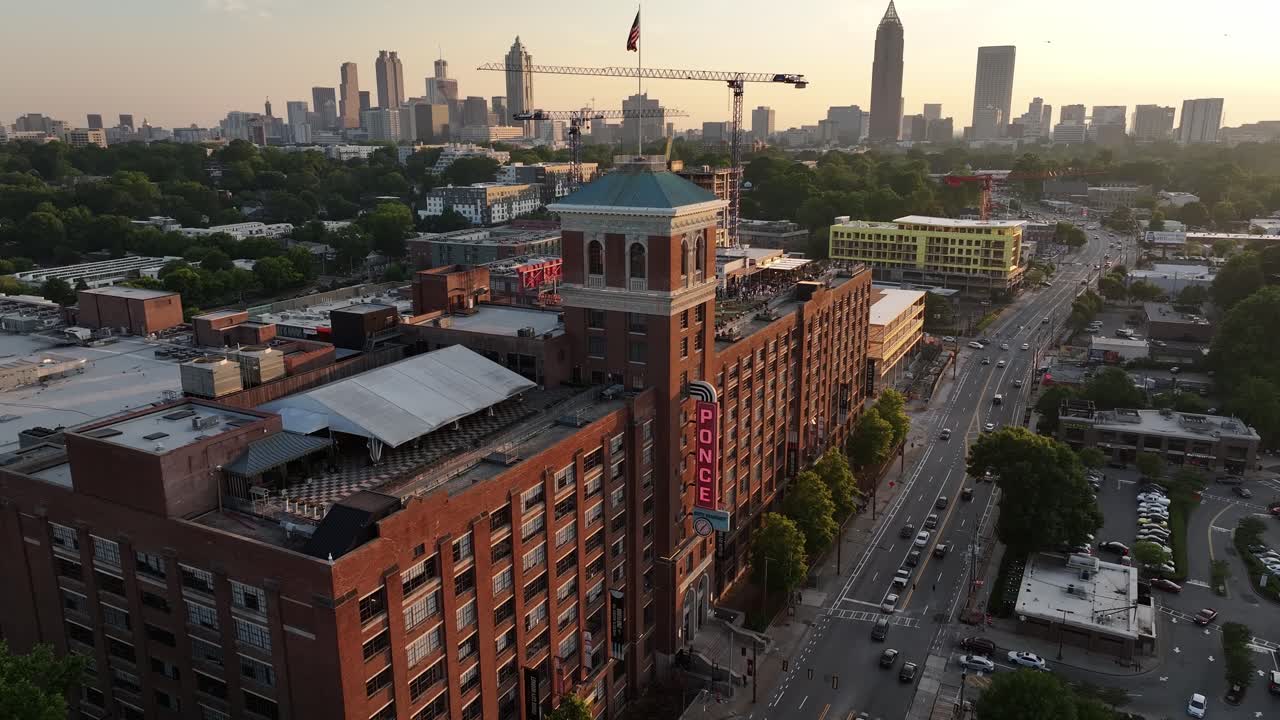aerial del edificio del mercado de ponce city y el vecindario bajo el cielo al atardecer, rascacielos de atlanta en el fondo, georgia, estados unidos