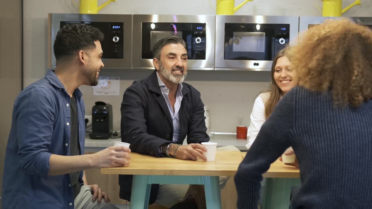 Happy manager enjoying coffee break with business employees in canteen