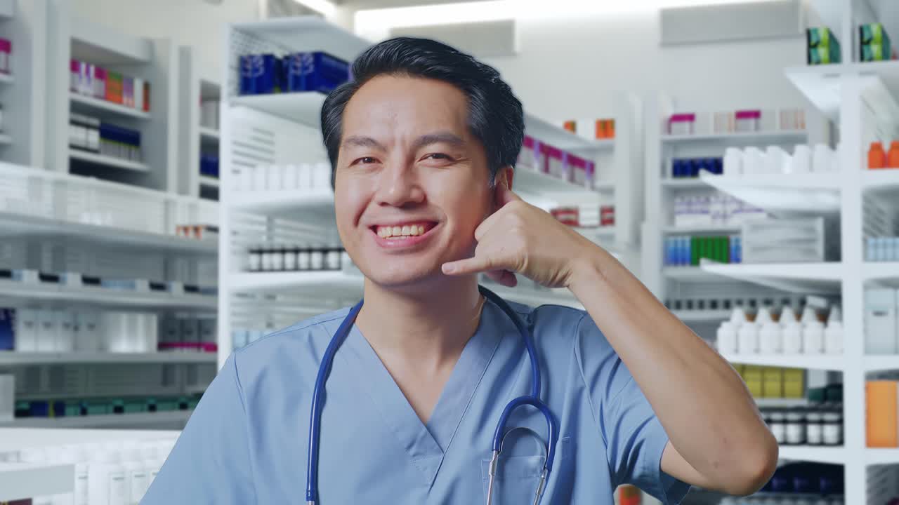 스테토스코프를 들고 있는 아시아 남성 의사의 클로즈업은 약국에서 나를 불러주고 웃는 몸짓을 보여준다.