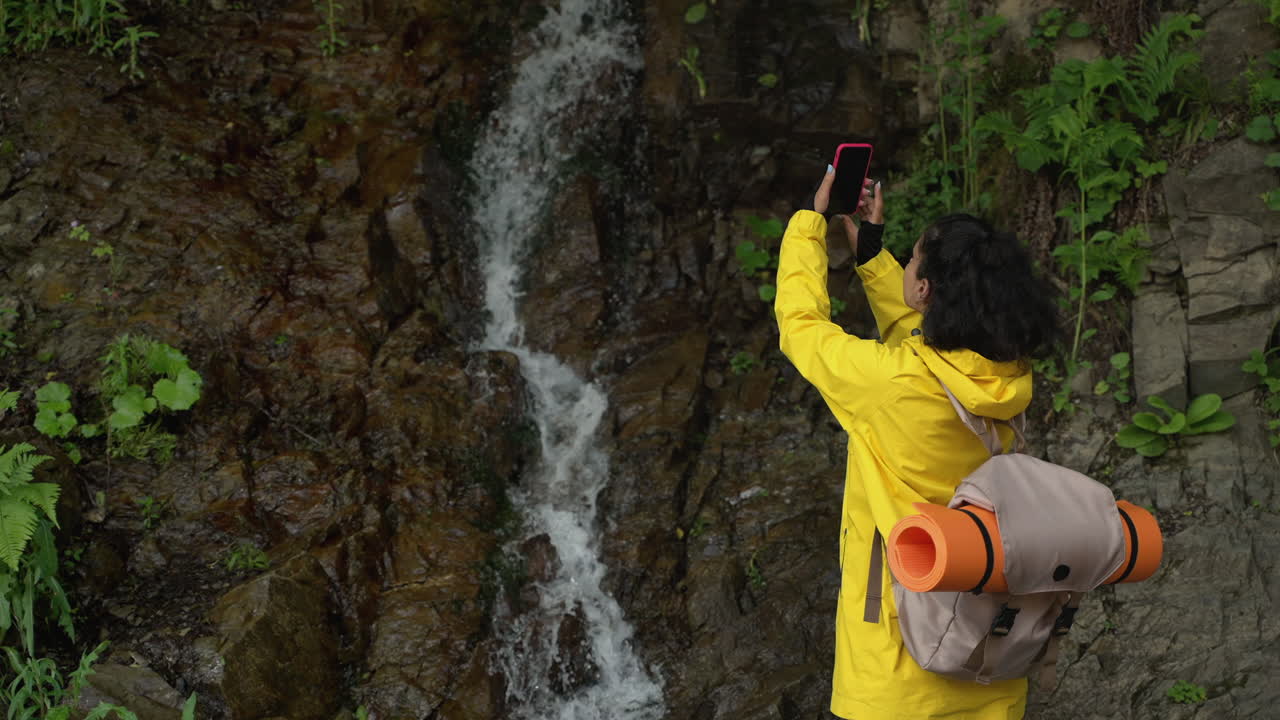 mujer tomando una foto de la cascada