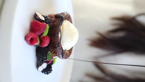 ein mann, der eine schokoladensauce auf einen kuchen zum dessert auf einem tisch in einem restaurant legt, close-up-schuss, schuss einfügen, vertikales video