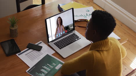 mujer afroamericana que usa una computadora portátil en una videollamada con una colega que trabaja desde casa