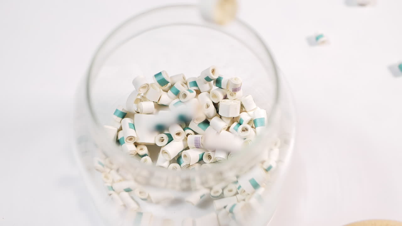 mini rollo de papel de deseos de amor, cayendo en un recipiente de vidrio en ángulo