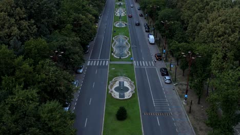 slow aerial reveal of the palace of parliament in bucharest, romania with a orange sky in the background at sunset, lush vegetation and water fountains underneath, slow backwards movement