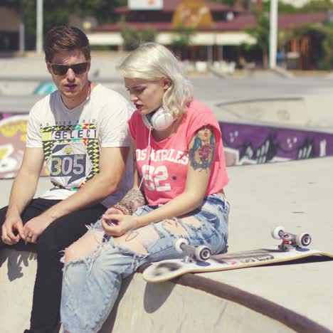 Young-couple-of-skateboarders-sitting-chatting