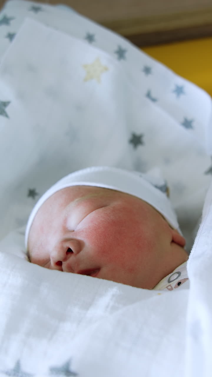 Peacefully sleeping Caucasian baby in a cute cap. Adorable newborn child in a blanket close up. Vertical video