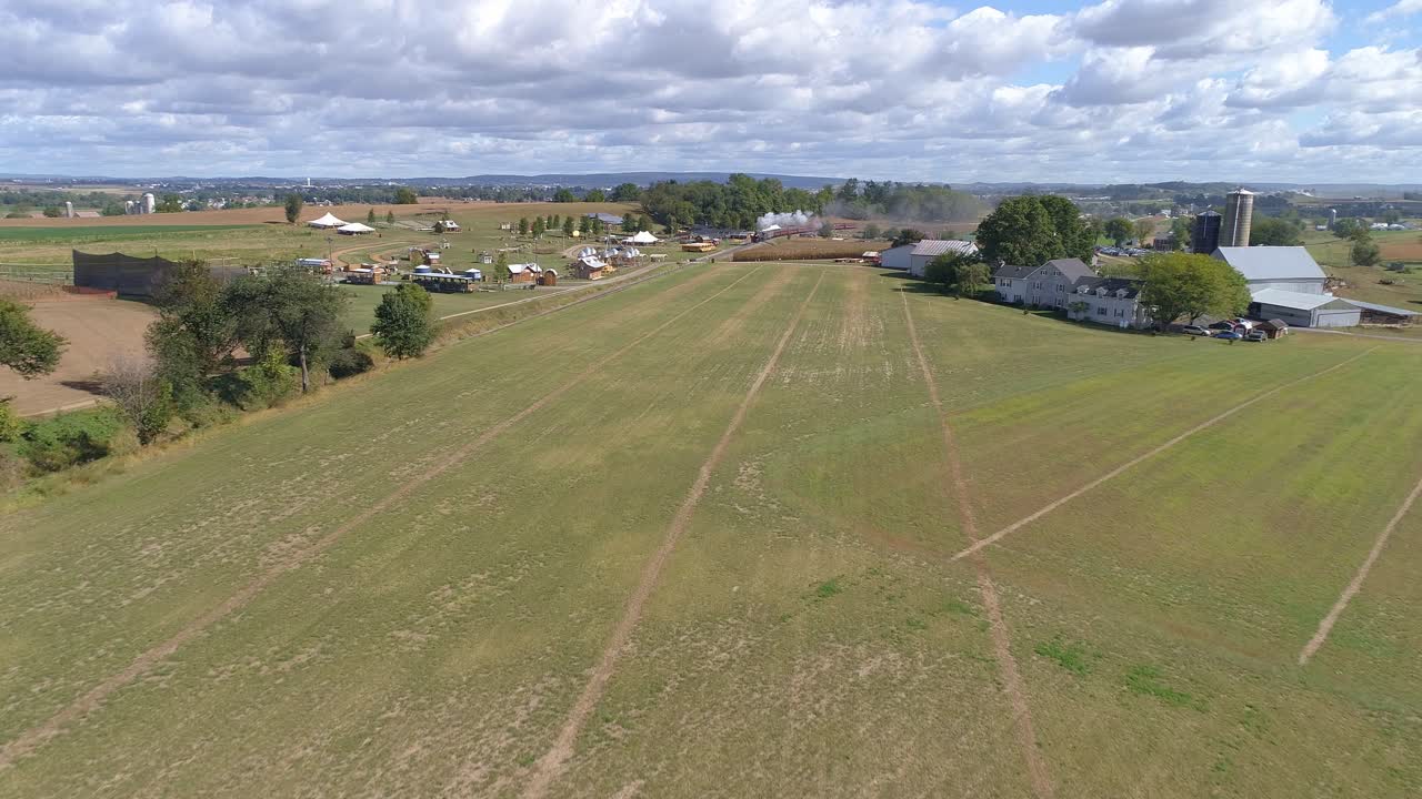 Aerial View of Farm Countryside with a Antique Steam Train Approaching Through it on a Sunny Partly Cloudy Day as Seen by a Drone