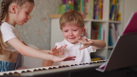 niña y niño con lágrimas comparan los dedos en las manos cerca del piano