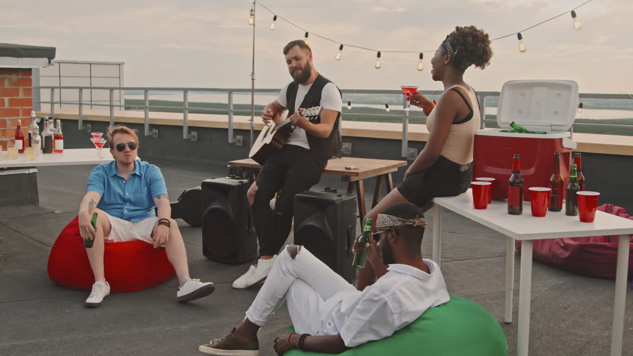 Man Playing Guitar for Friends at Rooftop Party