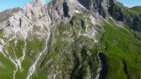 paisaje aéreo panorámico sobre el pico de los dolomitas en un día soleado de verano con cielos azules y cara de montaña verde y exuberante