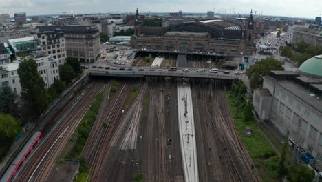 Forwards-fly-above-railway-tracks.-Tilt-up-reveal-of-historical-building-of-Hamburg-Hauptbahnhof-train-station.-Free-and-Hanseatic-City-of-Hamburg,-Germany