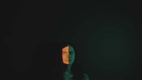 young man posing in dark room with light covering half of his face