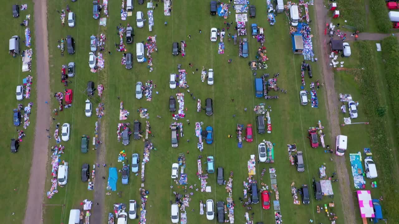 Birds-eye aerial view of a busy car boot sale with lifting reveal to the Derbyshire countryside