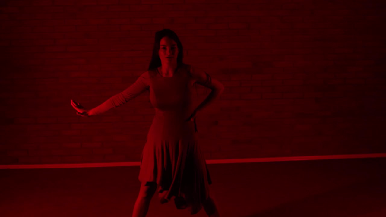 Danzatrice che volteggia e balla in una stanza rossa.