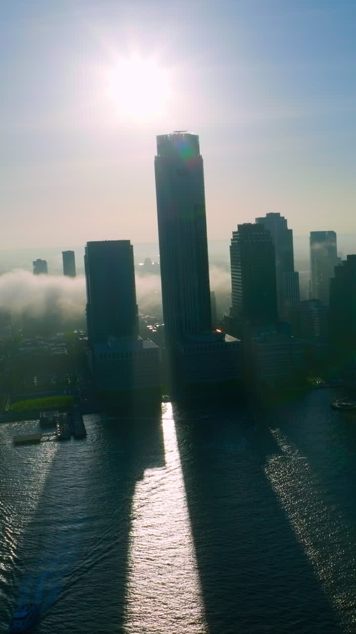 Evening falling on the beautiful New York city. White thick smoke crawling slowly from river to the island. Vertical video