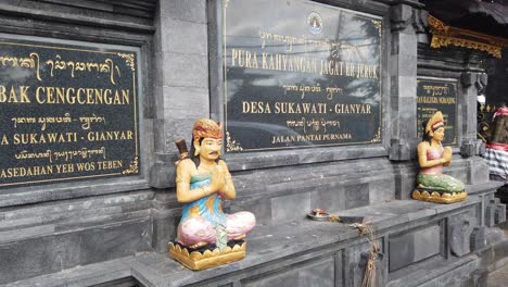 Estatua-Balinesa-De-Personas-De-Bali-Rezando,-En-La-Entrada-Del-Templo-De-Sukawati-En-La-Playa-De-Purnama,-Vistiendo-Ropa-Tradicional-Colorida,-Indonesia,-Sudeste-De-Asia,-Hinduismo