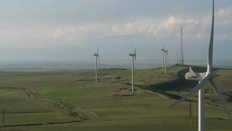 wind turbines at georgian wind farm spin creating clean energy, aerial slide right