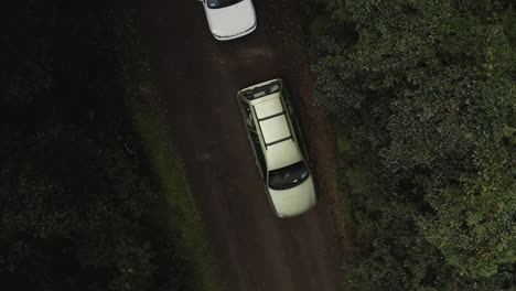 vista de arriba hacia abajo de 4k drones de autos blancos estacionados en un camino de tierra en un bosque verde en australia