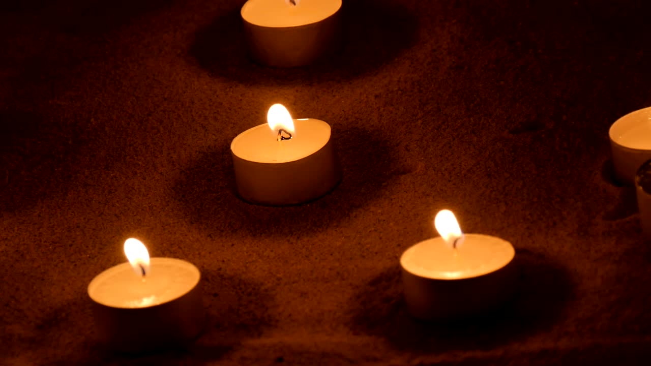 Candele che bruciano nella sabbia