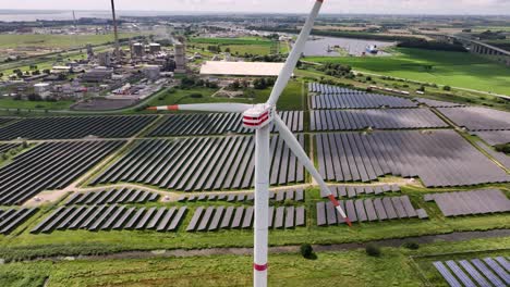a wind turbine standing in a solar field, generating renewable energy, drone orbit, green fields, parallax effect