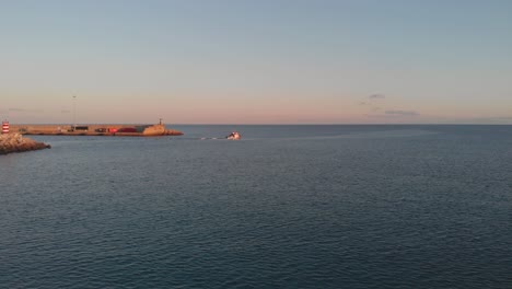 boat leaving port at sunset. aerial forward