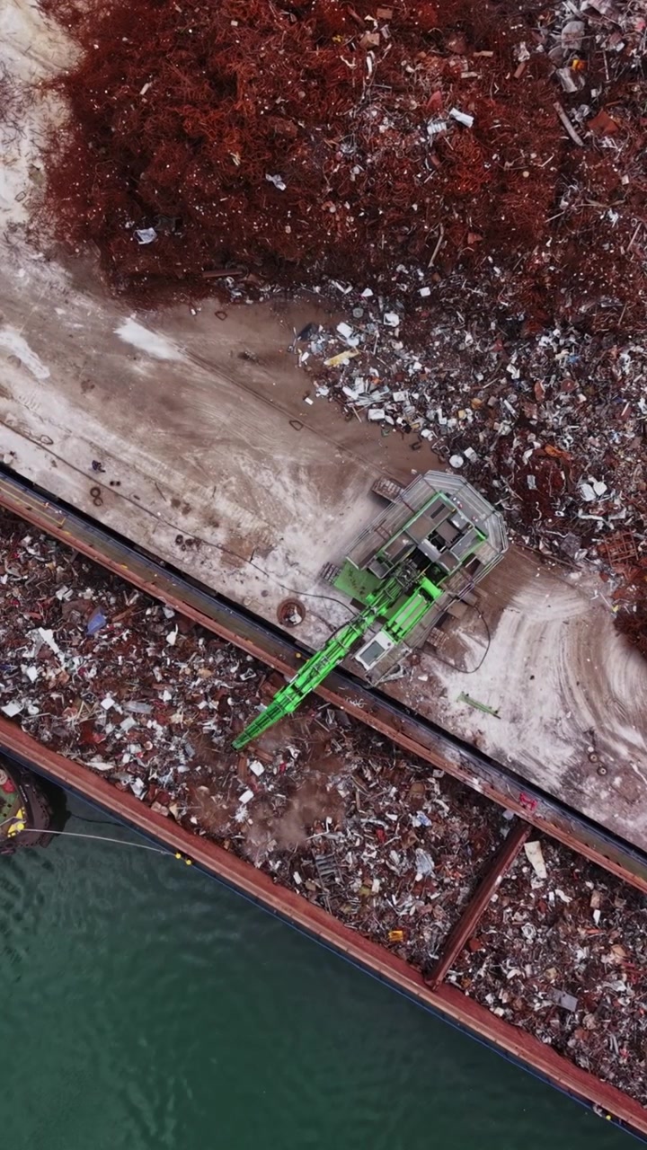 Ships unloading scrap metal at a recycling facility near the river