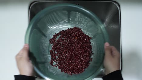 top down view of red beans being cleaned at kitchen sink