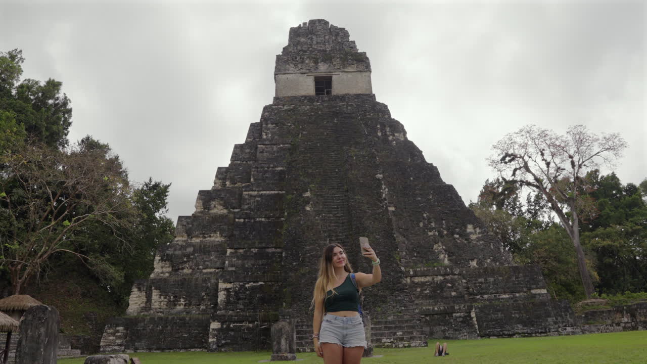 Traveler woman takes selfie with mobile. Tikal pyramid temple Guatemala. Digital nomad connectivity. Slow motion