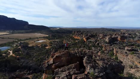 Male-rock-climber-standing-over-a-rocky-mountain-4k