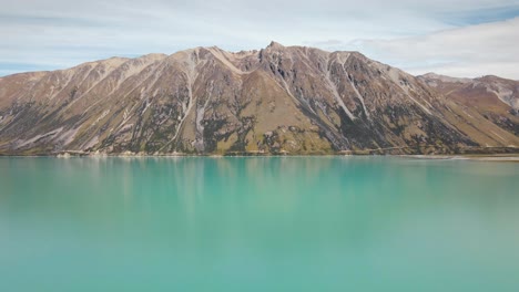 lago alpino con agua de glaciar derretida y majestuosa montaña escarpada en su orilla