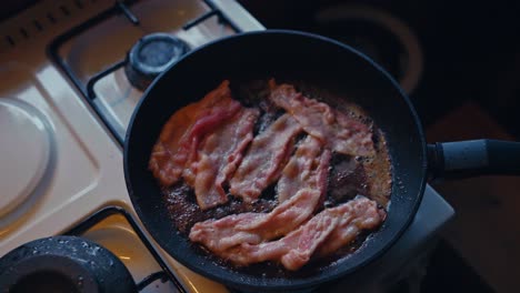 cooking fried bacon on the kitchen stove - breakfast meal. - high angle shot