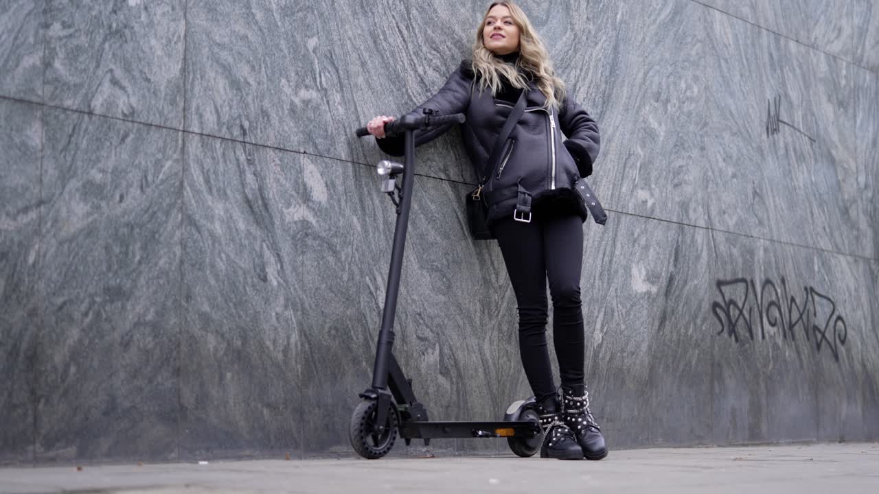 Woman with Electric Scooter by the Wall