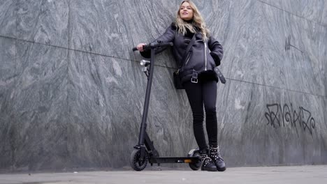 woman with electric scooter by the wall