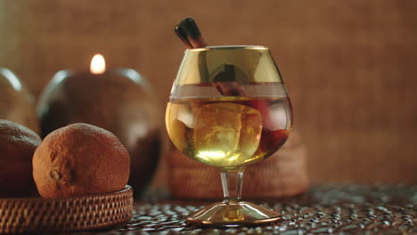 atmospheric product video of a balloon glass with brandy, whisky or cognac, with a vanilla stick and ice blocks rotating on a turntable display