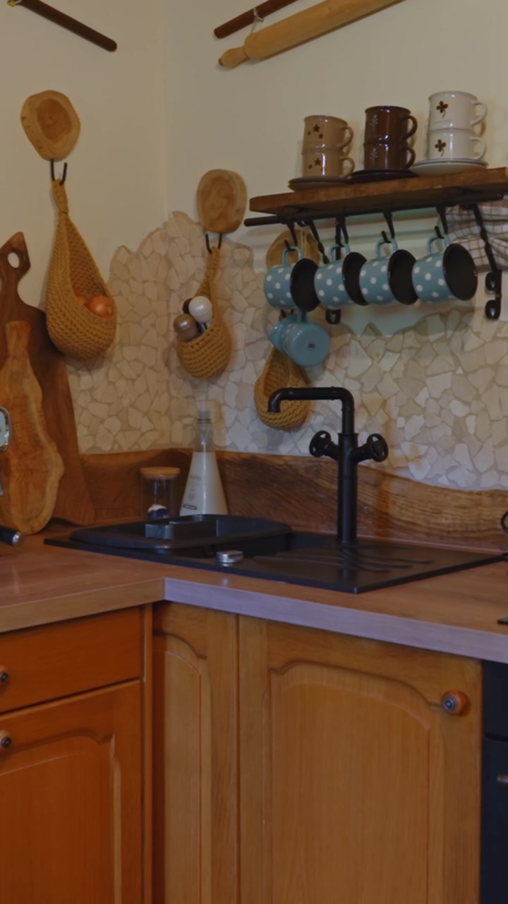 Incantevole angolo cucina rustico con mobili in legno, tazze in ceramica e paraschizzi a mosaico in video verticale, ideale per social media e storie