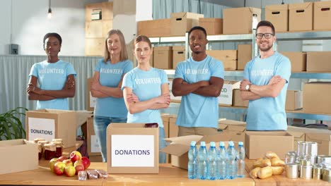 multiethnic group of volunteers standing in charity warehouse and smiling to the camera