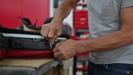 car seat upholstery repair in workshop, workers hands using knife