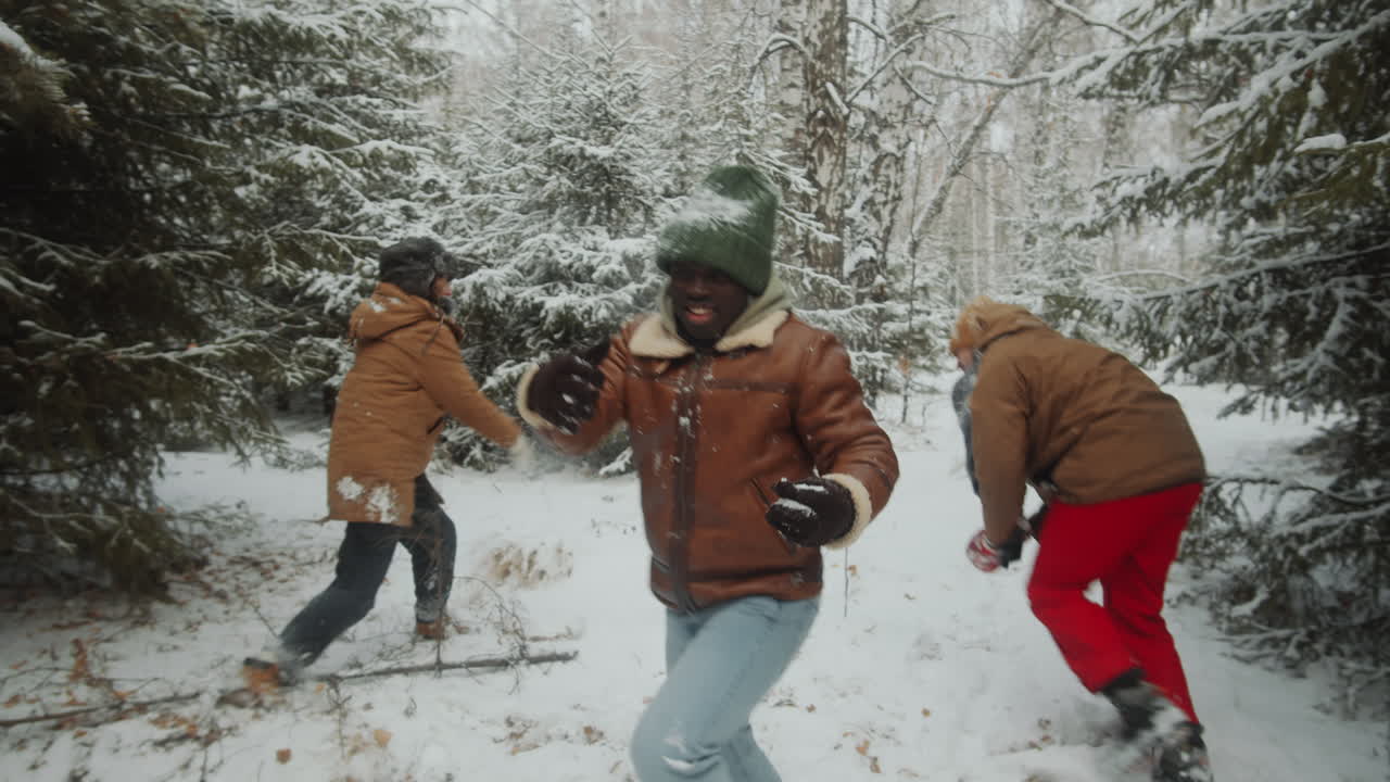 amigos emocionados jugando a las bolas de nieve en el bosque de invierno.