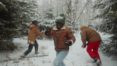 excited friends playing snowball fight in winter forest