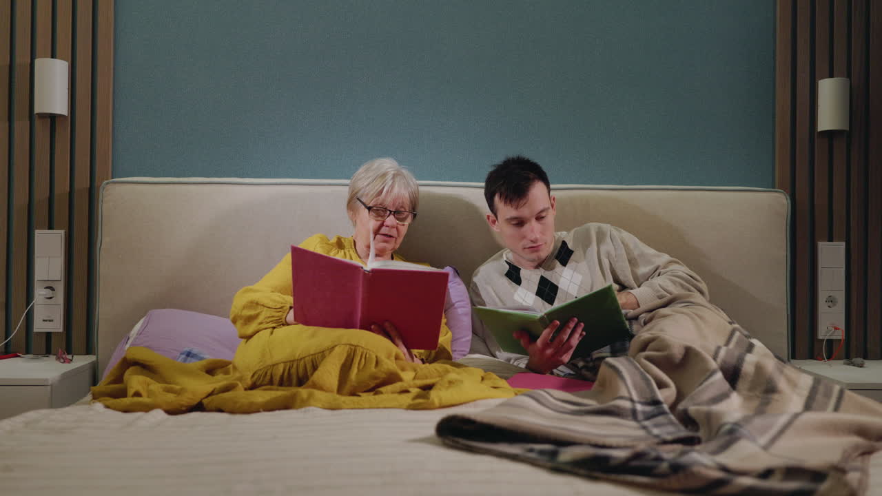 할아버지, 할머니와 손자가 침대에서 읽고 있습니다.