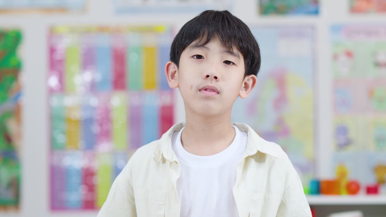 Happy elementary student proudly holds orange foam number six in bright classroom, static camera shot