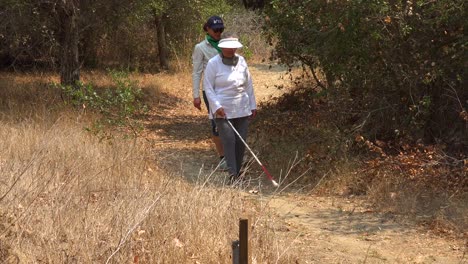una mujer ciega camina con un bastón a través de un área natural con un guía que la ayuda a explorar el desierto 4