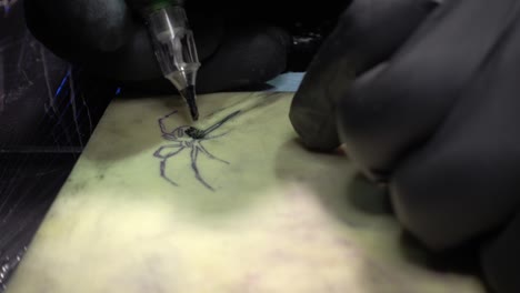 a tattoo artist drawing a tattoo of a black widow