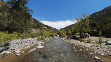 flying along river bed in rocky cajon del maipo canyon in chile, fpv low flying shot